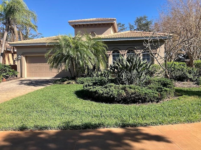 view of front of home featuring a garage, a tiled roof, a front yard, and driveway