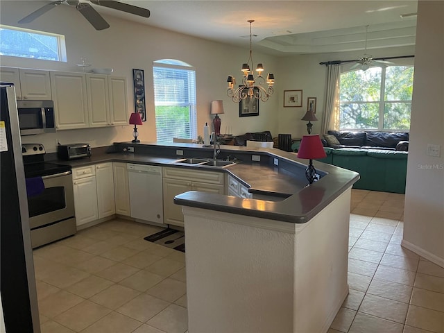 kitchen with light tile patterned floors, dark countertops, appliances with stainless steel finishes, open floor plan, and a sink