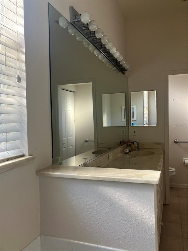 full bath with tile patterned floors, a sink, toilet, and double vanity