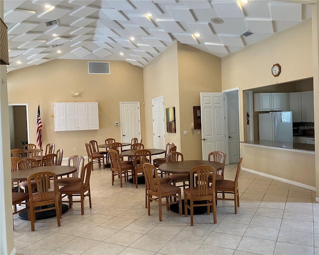 dining room with light tile patterned floors, visible vents, and high vaulted ceiling