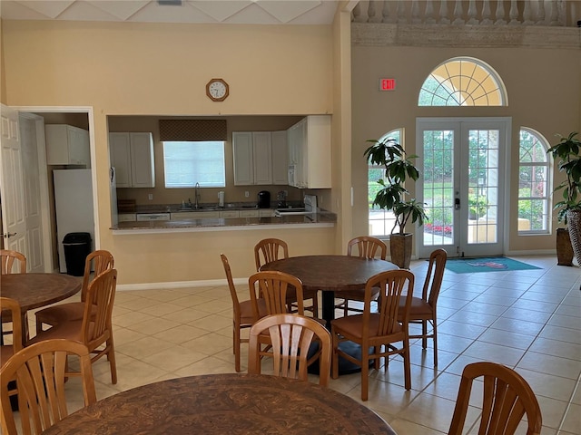 dining space with french doors, a high ceiling, baseboards, and light tile patterned floors