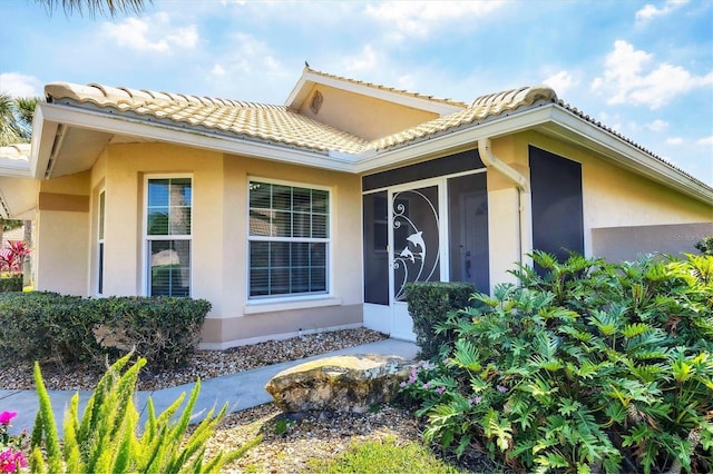 property entrance with a tile roof and stucco siding