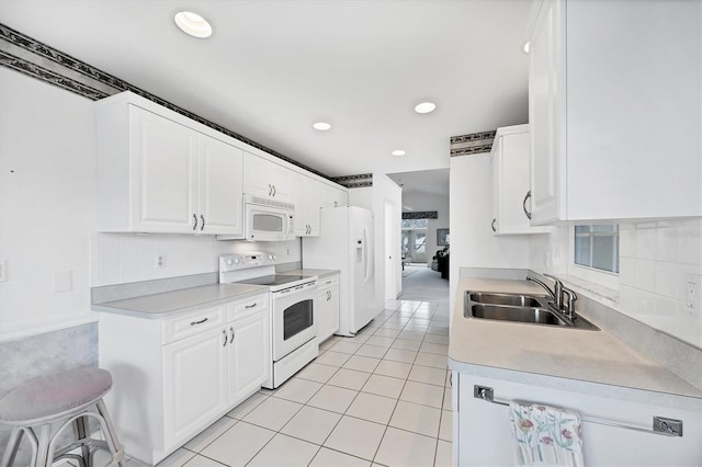 kitchen with light tile patterned floors, light countertops, white cabinetry, a sink, and white appliances