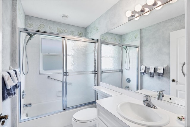 full bathroom with enclosed tub / shower combo, vanity, and toilet