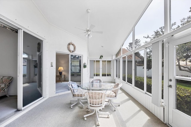 sunroom with a healthy amount of sunlight, a ceiling fan, and lofted ceiling