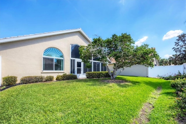 exterior space featuring fence, a front lawn, and stucco siding