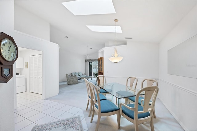 dining area featuring vaulted ceiling with skylight, washer / clothes dryer, light carpet, and light tile patterned flooring