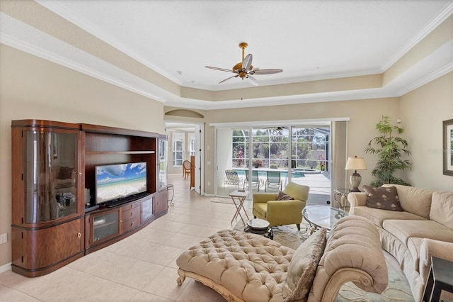 living area with a tray ceiling, crown molding, baseboards, and light tile patterned floors