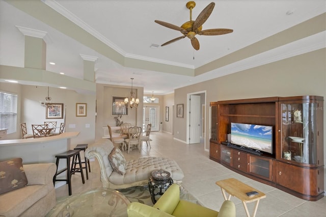 living area with baseboards, a raised ceiling, ornamental molding, light tile patterned flooring, and ceiling fan with notable chandelier