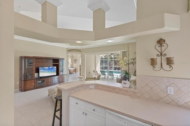 kitchen featuring a breakfast bar, light tile patterned floors, light countertops, white cabinetry, and dishwasher