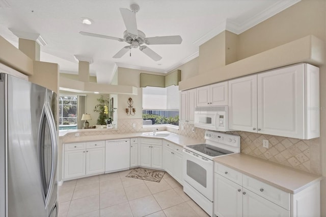 kitchen featuring white appliances, white cabinets, ornamental molding, a sink, and backsplash