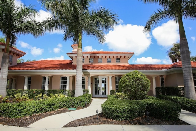 view of front of house with stucco siding, a tile roof, and french doors