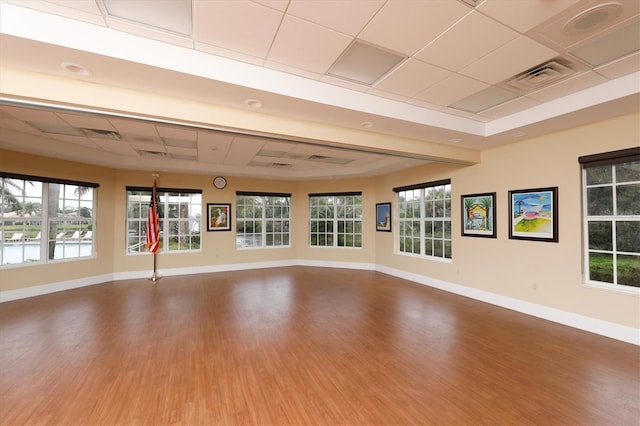 unfurnished room with a drop ceiling, wood finished floors, visible vents, and baseboards