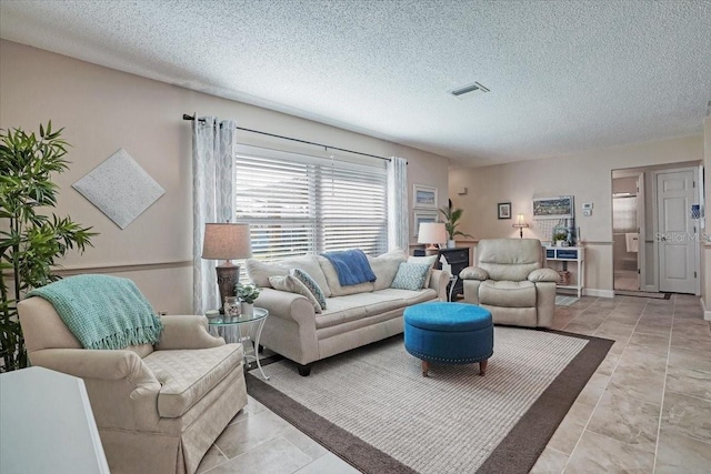 living room featuring light tile patterned floors, visible vents, and a textured ceiling