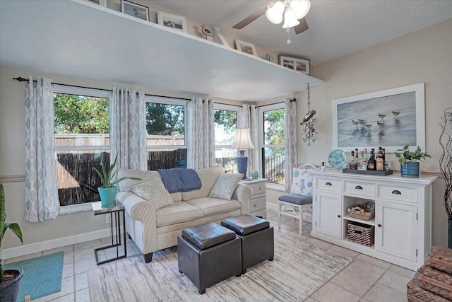 living area featuring light tile patterned floors, plenty of natural light, a textured ceiling, and baseboards