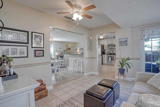 living room featuring light tile patterned flooring, baseboards, visible vents, and a textured ceiling