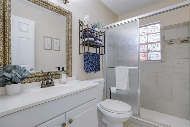 full bath with vanity, toilet, a shower stall, and a textured ceiling