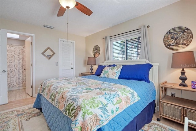 bedroom featuring visible vents, a textured ceiling, ensuite bath, wood finished floors, and a closet