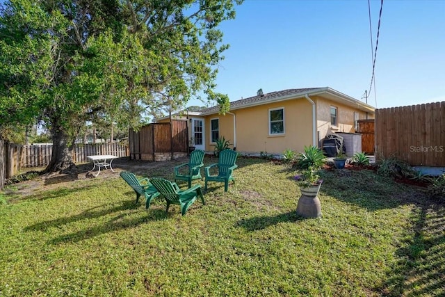 back of house featuring stucco siding, a lawn, and a fenced backyard