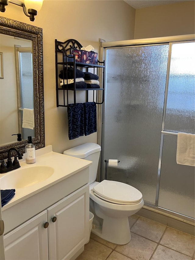 bathroom featuring tile patterned floors, a stall shower, toilet, and vanity