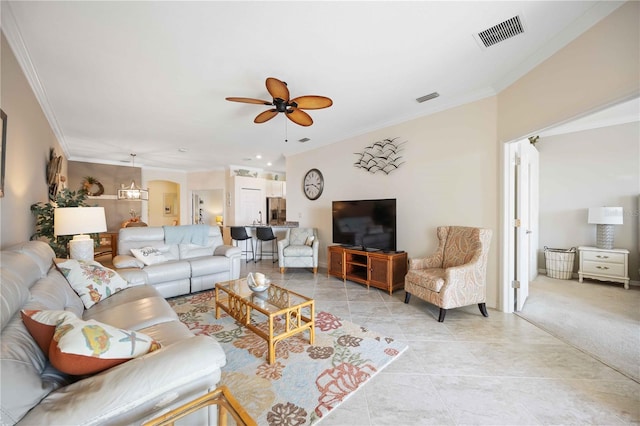 living room featuring ceiling fan, visible vents, arched walkways, and ornamental molding