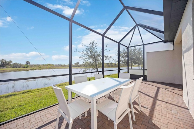 view of patio featuring glass enclosure, a water view, and outdoor dining area