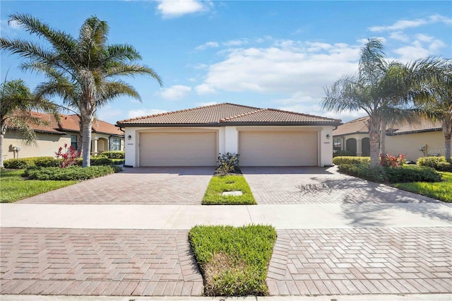 view of front facade featuring a garage, a tiled roof, decorative driveway, and stucco siding