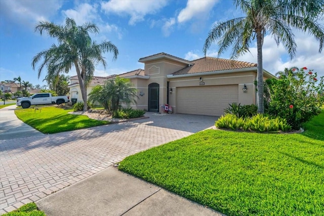 mediterranean / spanish-style house featuring decorative driveway, an attached garage, a front lawn, and stucco siding