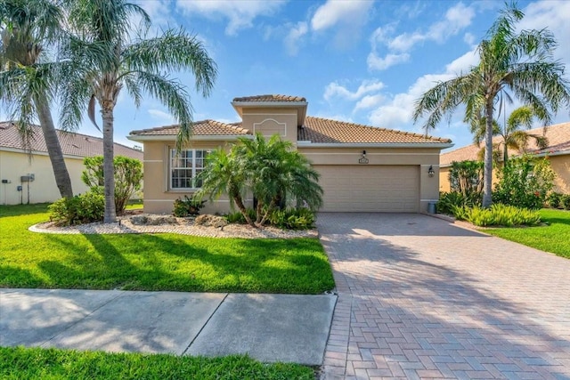 mediterranean / spanish home with stucco siding, an attached garage, decorative driveway, and a front lawn