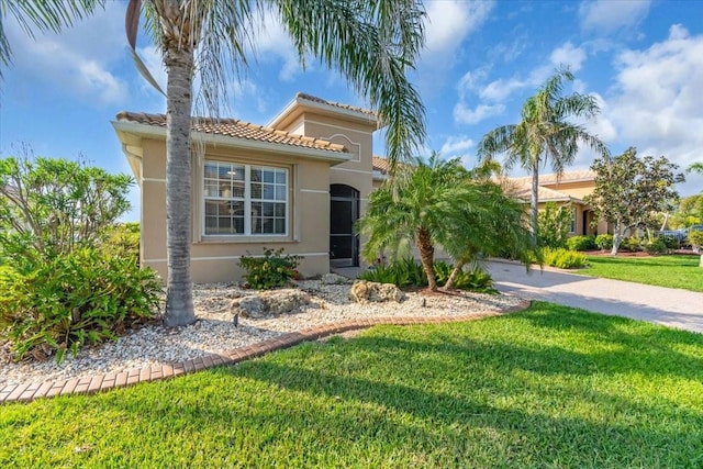 mediterranean / spanish home featuring a front lawn, a tiled roof, and stucco siding