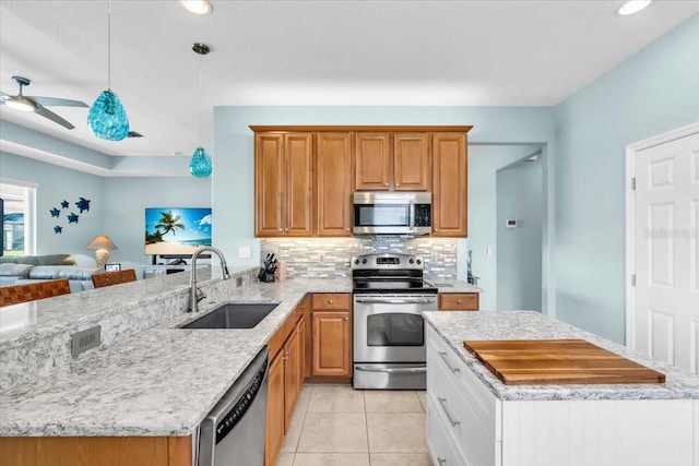 kitchen with a sink, backsplash, stainless steel appliances, a peninsula, and light stone countertops