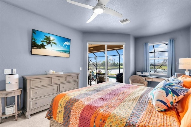 bedroom featuring visible vents, access to outside, a textured ceiling, a sunroom, and light colored carpet