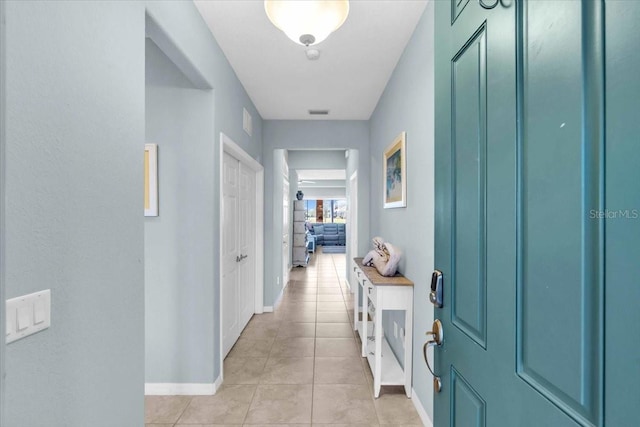 hall featuring baseboards and light tile patterned flooring