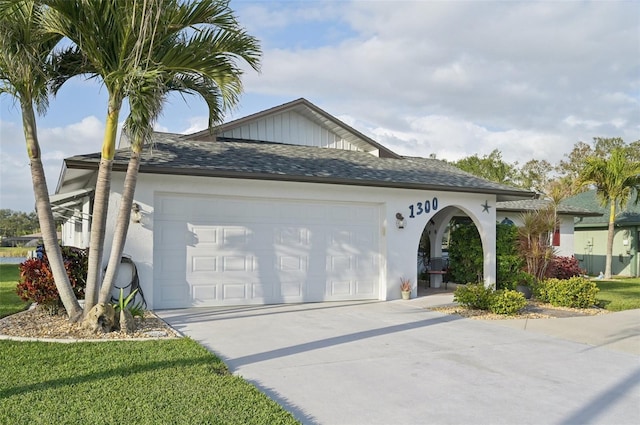 view of front of house with an attached garage, a shingled roof, driveway, stucco siding, and a front yard