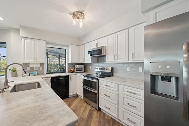 kitchen featuring stainless steel appliances, wood finished floors, a sink, and tasteful backsplash