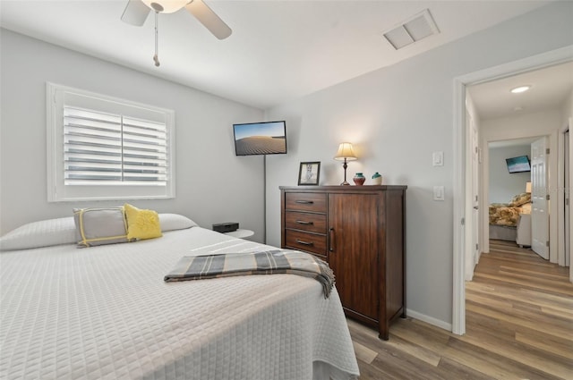 bedroom featuring baseboards, visible vents, ceiling fan, and wood finished floors