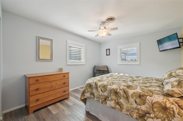 bedroom featuring visible vents, ceiling fan, baseboards, and wood finished floors