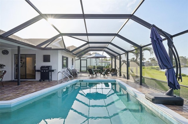 pool featuring glass enclosure, a patio area, and a grill