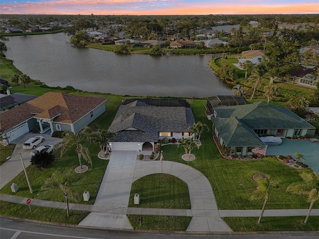 aerial view at dusk featuring a water view and a residential view