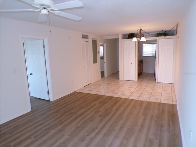 unfurnished room with ceiling fan with notable chandelier, visible vents, and light tile patterned flooring