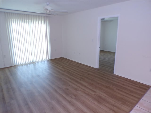 empty room with a ceiling fan, baseboards, and wood finished floors