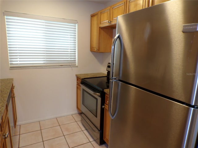 kitchen with stainless steel appliances, light tile patterned flooring, and brown cabinets