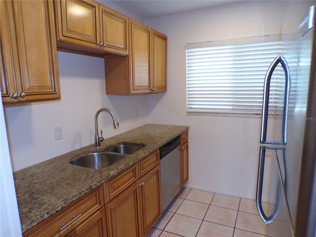 kitchen with light tile patterned floors, brown cabinetry, stainless steel appliances, stone counters, and a sink