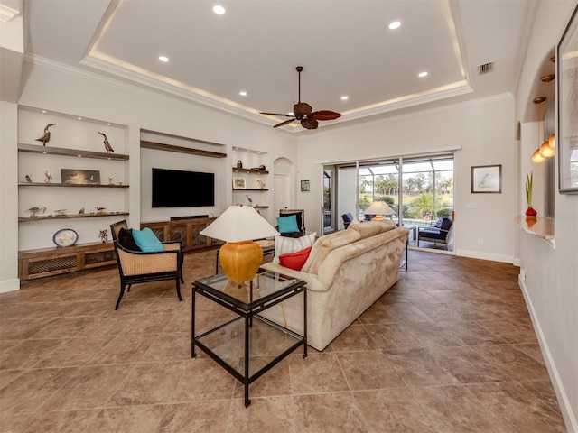 living room featuring baseboards, a tray ceiling, and crown molding