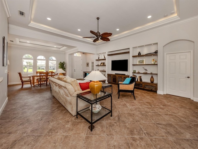 living area with visible vents, a raised ceiling, built in features, and ornamental molding