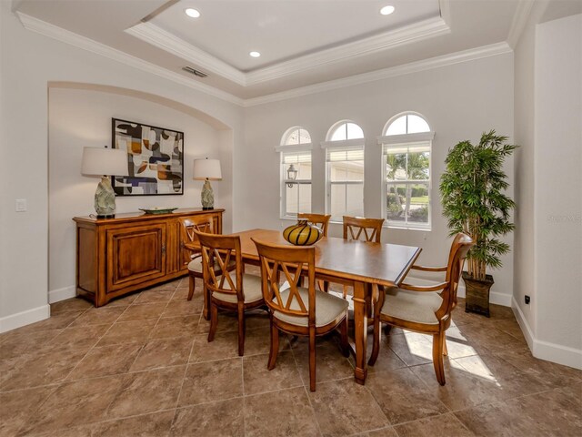 dining area with baseboards, a tray ceiling, visible vents, and crown molding