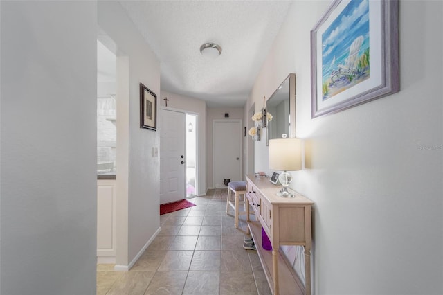 hallway featuring baseboards and a textured ceiling