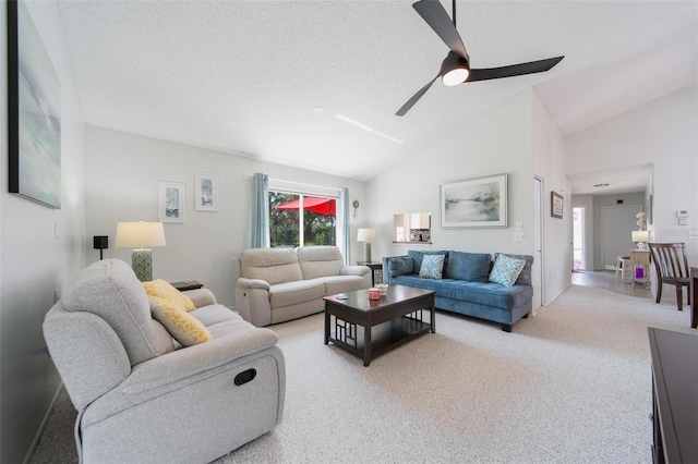 living room featuring lofted ceiling, ceiling fan, a textured ceiling, and light colored carpet