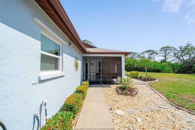 doorway to property with a yard and stucco siding