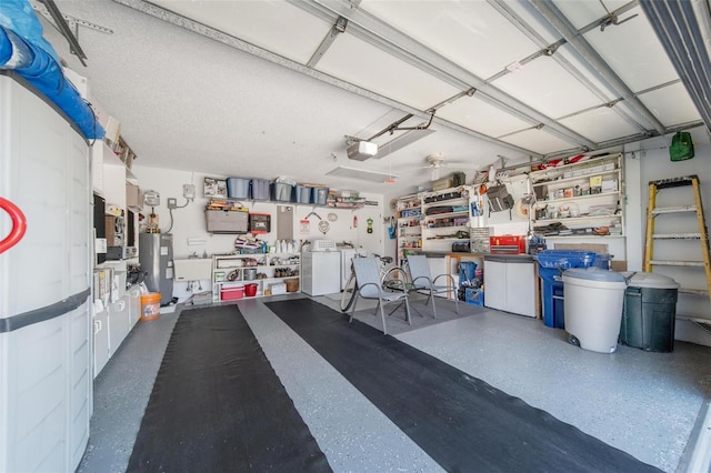 garage with water heater, a garage door opener, and independent washer and dryer